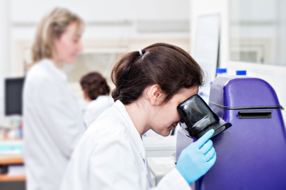 trabajadora de un laboratorio observando a través de un microscopio